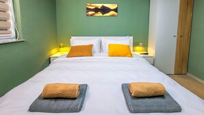Een hotelkamer met een bed, twee bedlampen, een schilderij aan de muur en een kledingkast.