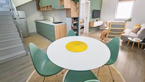 Een ruimtelijke leefruimte met keuken, eethoek en zithoek.