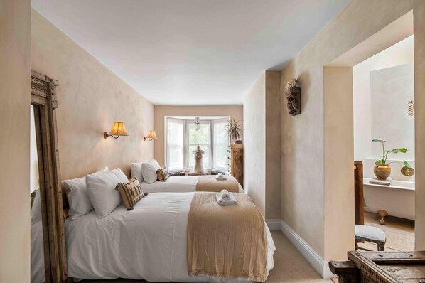 A hotel room with two beds, a large mirror, a vanity with a plant, and a view of the outdoors. - Sanctuary House With Parking By My Getaways (Shoreham-by-Sea)