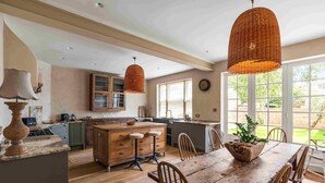 Cocina con armarios de madera, una isla central con taburetes y lámparas colgantes de mimbre.