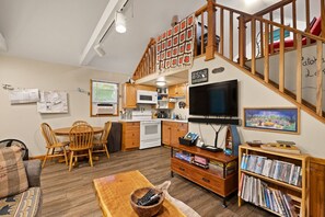 A compact living space with a kitchen, dining area, and a staircase leading to a loft.