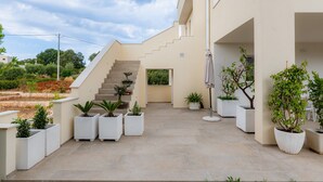A modern building with a staircase, potted plants, and a clear sky. - Apartment 'Flora' with Private Garden, Wi-Fi, and Air Conditioning (Cisternino)