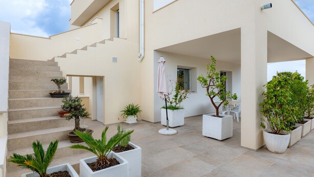 A modern building with a staircase, potted plants, and a clean, minimalist design. - Apartment 'Flora' with Private Garden, Wi-Fi, and Air Conditioning (Cisternino)