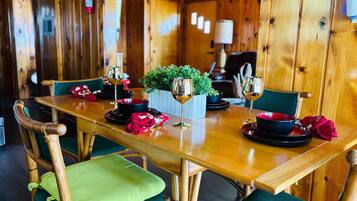 A wooden dining table with chairs, a fire extinguisher on the wall, and a small potted plant on the table.
