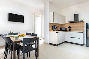 Une cuisine moderne avec des armoires blanches, un four à micro-ondes et une cuisinière intégrée.