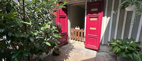 A stone-paved entrance with red doors and a wooden fence.