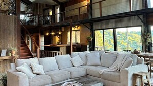 A spacious living area with a large sectional sofa, a wooden coffee table, and a staircase leading to an upper level.