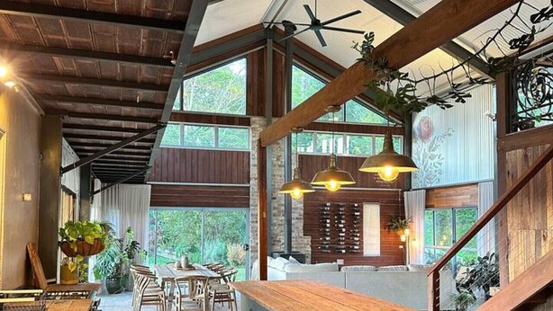 A spacious kitchen with a central island, wooden beams, and large windows.