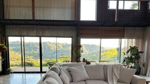 A spacious living room with a large sectional sofa, a coffee table, and a view of a mountainous landscape through large windows.