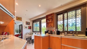 A modern kitchen with a central island, wooden cabinets, and a window with decorative iron bars.