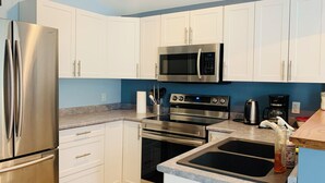Una cocina moderna con electrodomésticos de acero inoxidable, armarios blancos y encimera de granito.