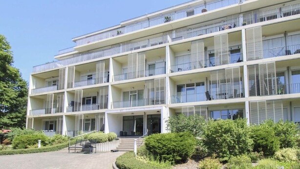 A multi-story building with balconies, a central entrance, and a landscaped garden area. - Südwind 05 - apartment, close to the beach, swimming pool, sauna, parking, WLAN, and balcony (Zempin)
