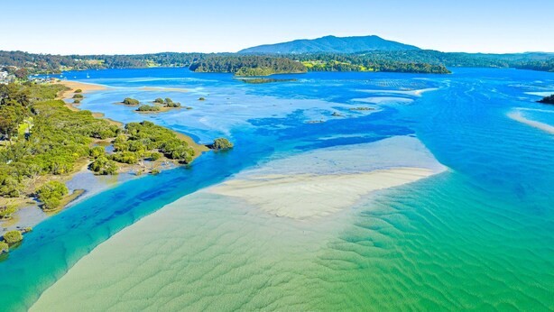 An aerial view of a coastal area with clear blue waters, sandy beaches, and green vegetation. - Nestle In Narooma - 10 Hillcrest Ave North Narooma (North Narooma)