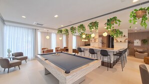 Ett modernt vardagsrum med biljardbord, bardisk och sittgrupp.
