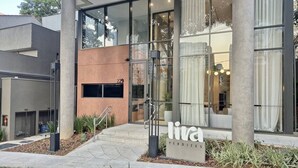 En modern byggnad med stora glasfönster, en entré i betong och en skylt med texten ”liva PERDIZES”.
