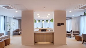 En modern hotellobby med en central ö, sittgrupper och utsikt över omgivningarna.