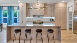 A modern kitchen with a central island, bar stools, and a pendant light. - Fabulous 5-bedroom house in Dallas (Dallas)