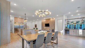A modern kitchen with built-in appliances, a dining area with a wooden table and chairs, and a large chandelier. - Fabulous 5-bedroom house in Dallas (Dallas)