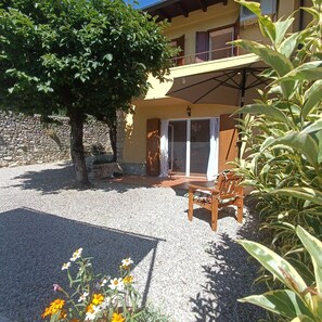 Un bâtiment avec un mur en pierre, un arbre et un espace patio comprenant une chaise et une table.