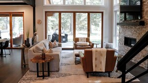 A spacious living room with a large window, a fireplace, and a staircase.
