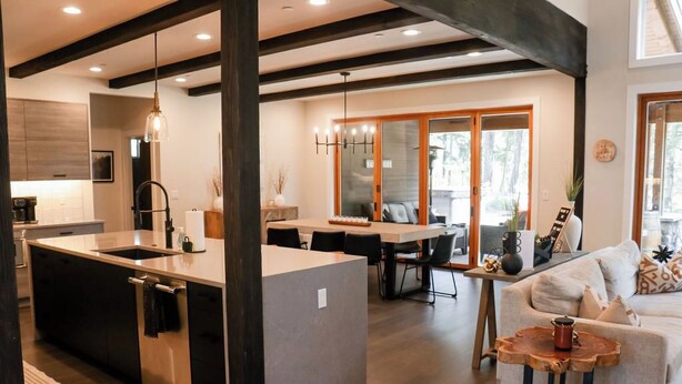 A modern kitchen with a central island, a dining area with a table and chairs, and a living area with a sofa and a coffee table.