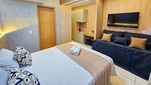 Une chambre d’hôtel comprenant un lit, un canapé, une télévision et une kitchenette.