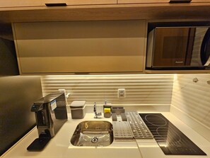 A modern kitchen with a built-in microwave, stainless steel sink, and a compact coffee maker. - Makia - Porto de Galinhas  (Ipojuca)