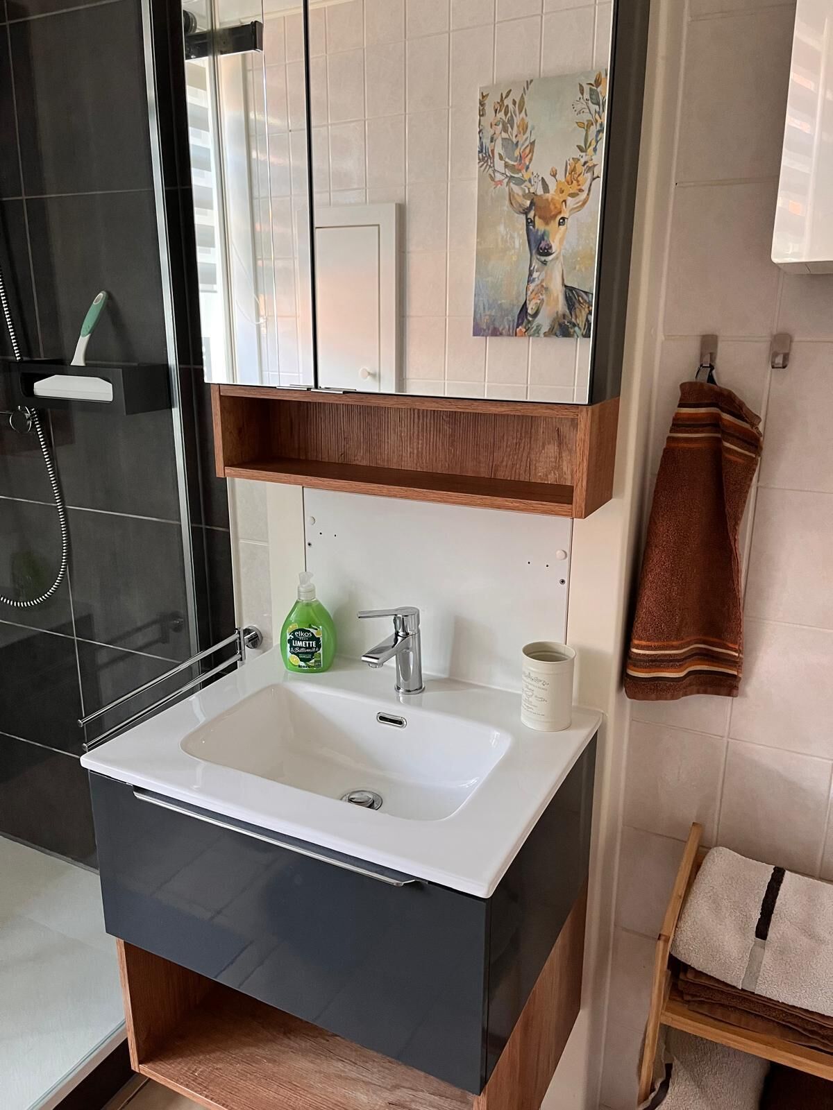 A bathroom with a white sink, a mirror, a green bottle of shampoo, and a towel rack.