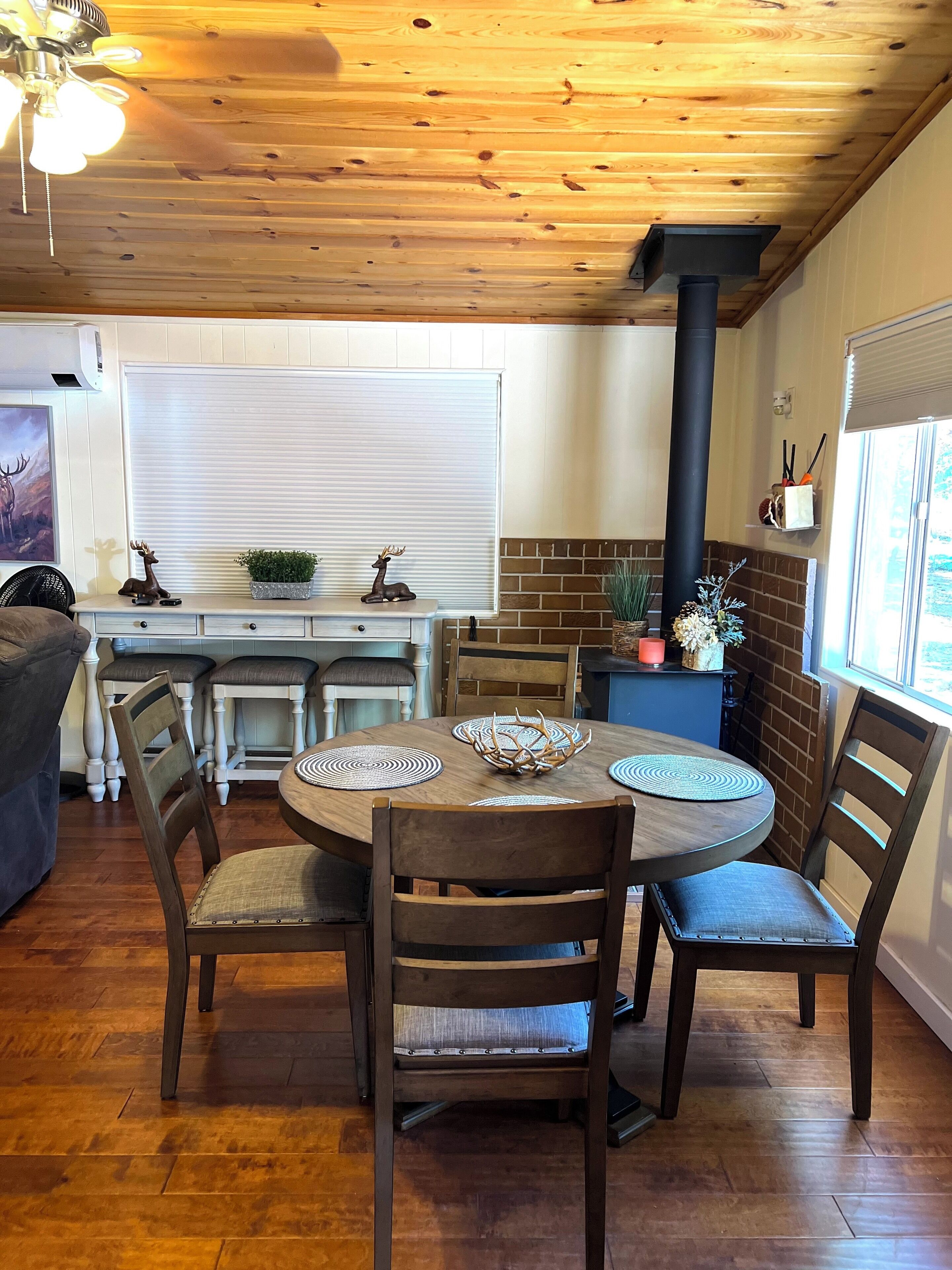 Un coin repas comprenant une table ronde en bois, quatre chaises et un élément décoratif central en forme de bois de cerf.