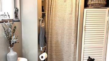 Une salle de bain équipée de toilettes, d’un rideau de douche, d’un porte-serviettes et d’une statue d’ours décorative.