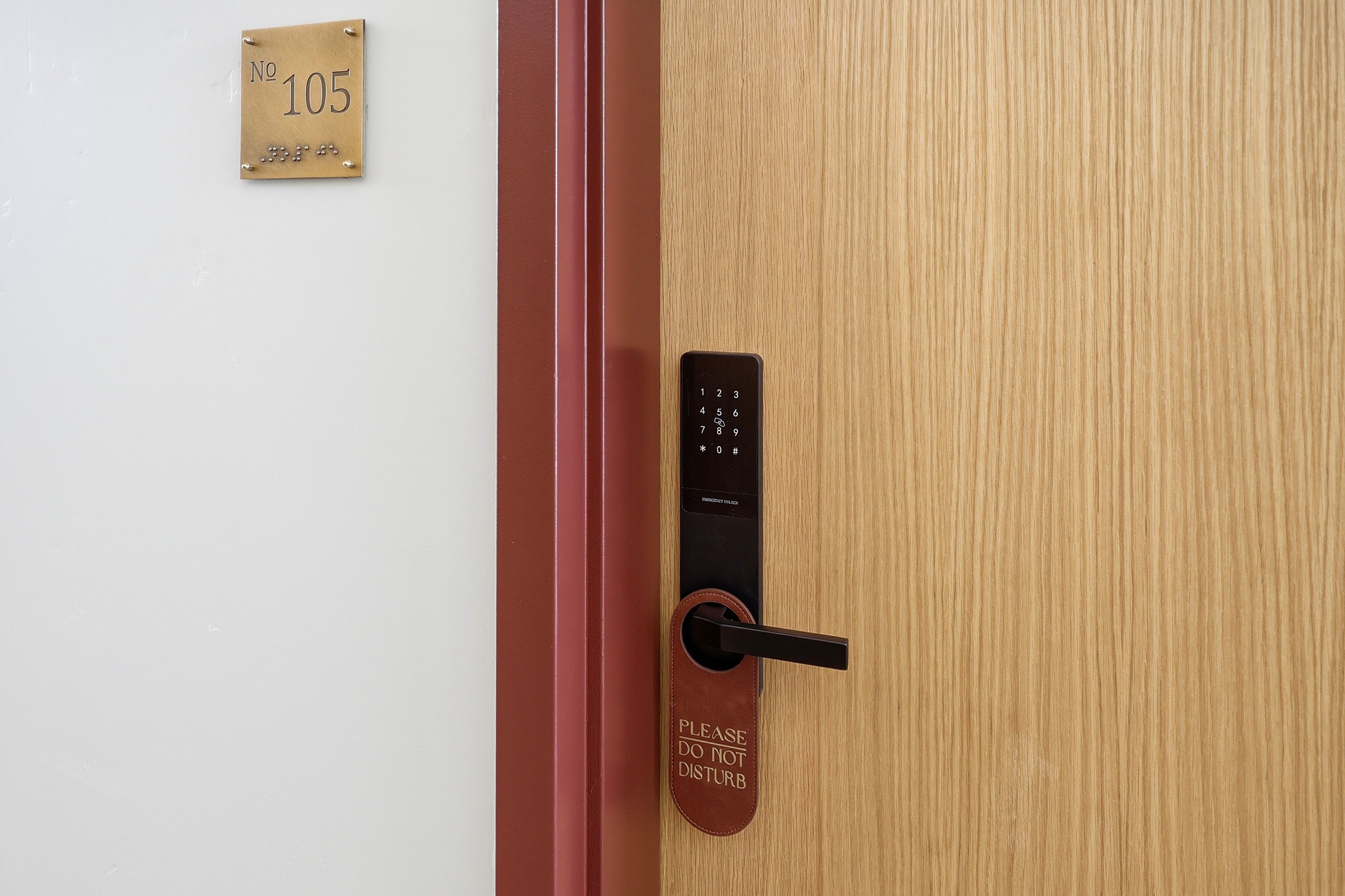 A door with a numeric keypad lock, a 'Please do not disturb' sign, and a room number sign.