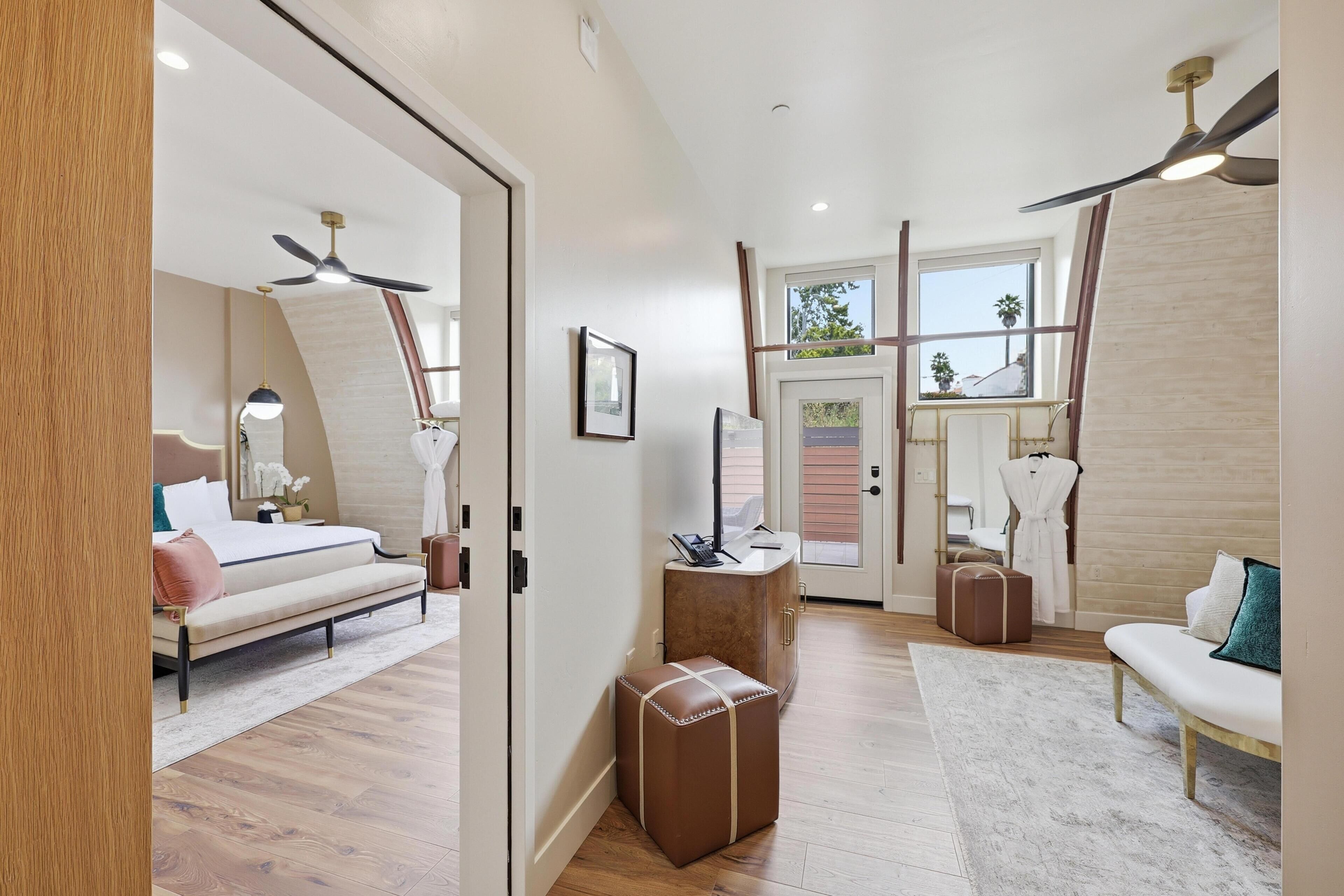 A modern hotel room with a bed, seating area, and a desk.