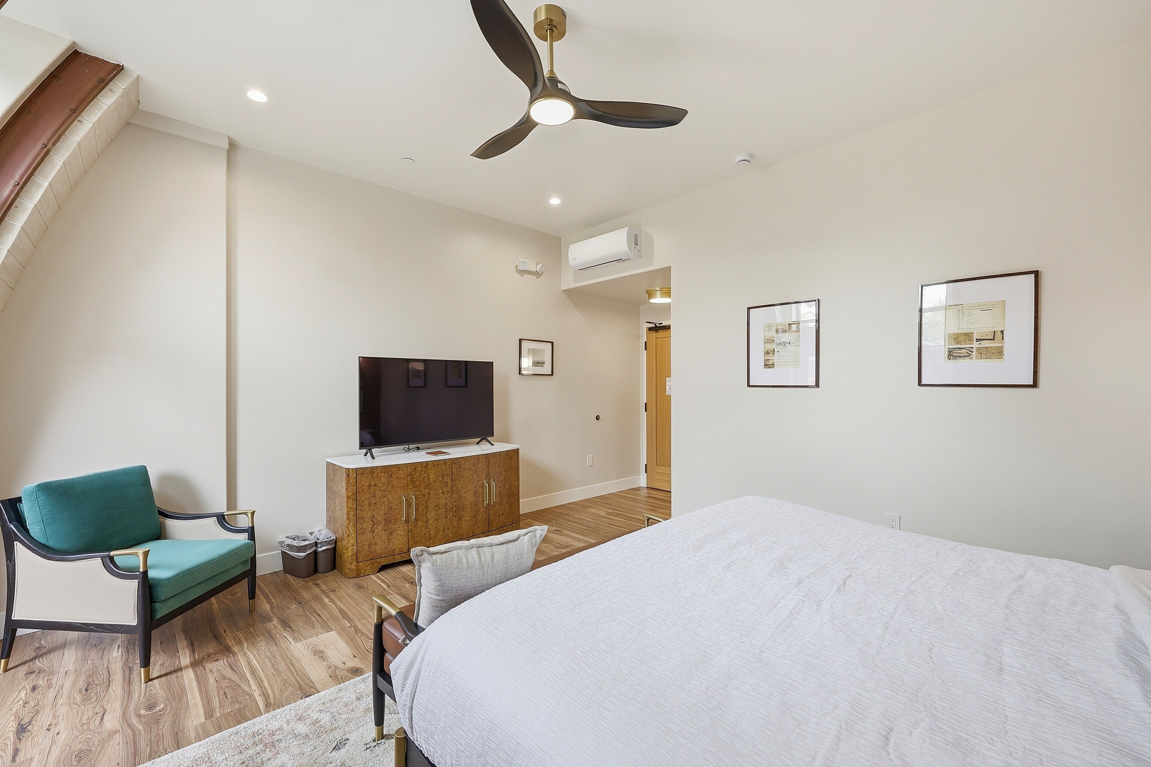 A bedroom with a bed, a television, a desk, and a chair.