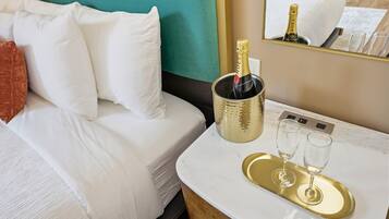 A hotel room with a bed, a minibar, a tray with two glasses, and a bottle of champagne.