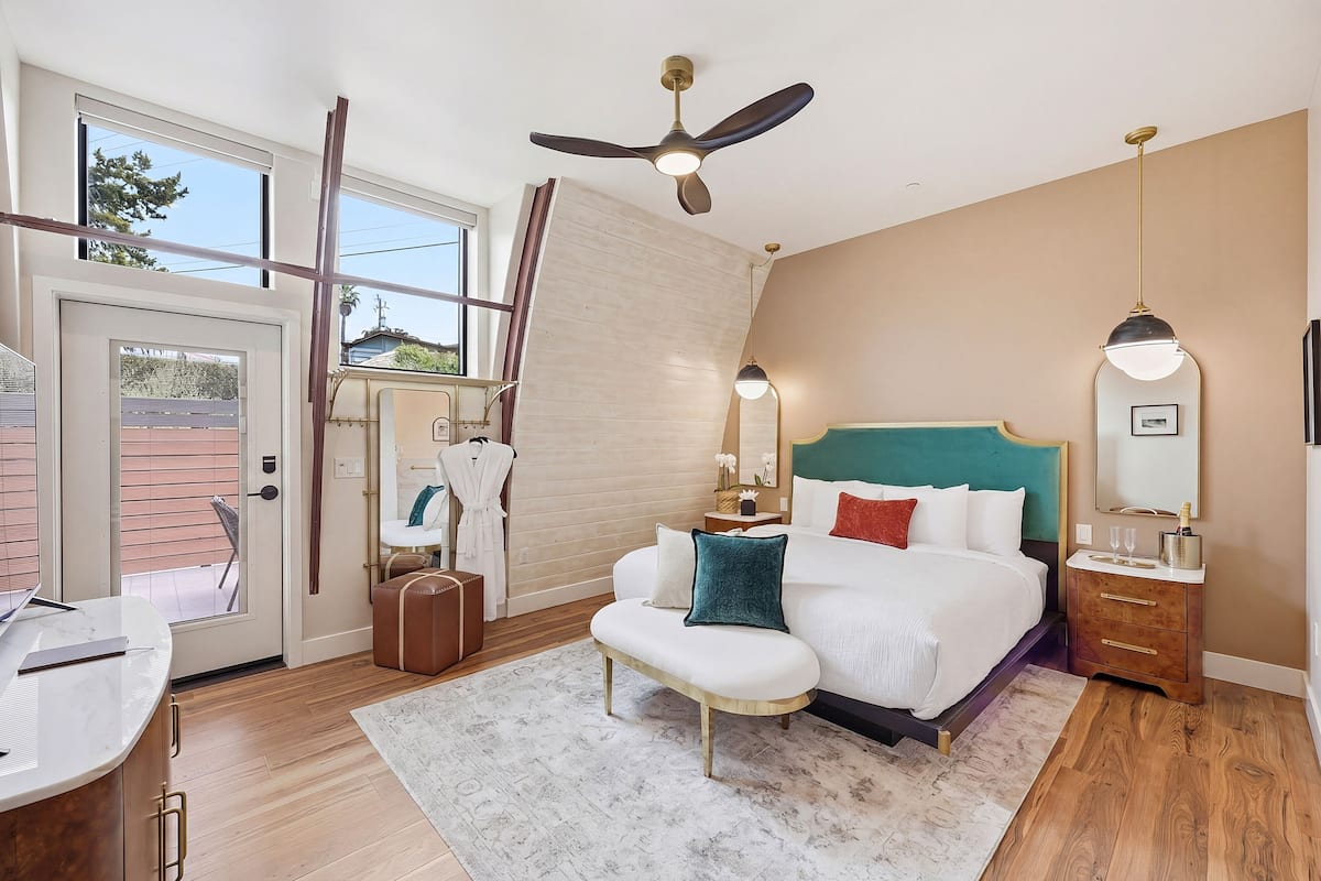 A bedroom with a bed, bedside tables, a desk, a ceiling fan, and a window.