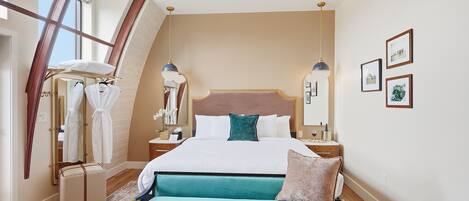 Un dormitorio con una cama, un banco, un espejo y cuadros en la pared.