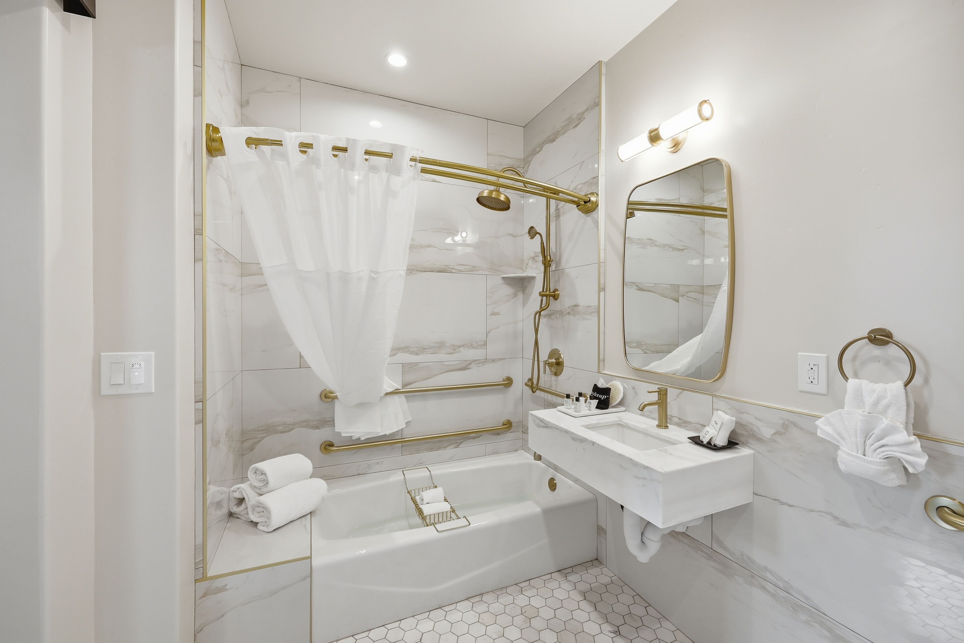 A modern bathroom with a bathtub, vanity, and a large mirror.