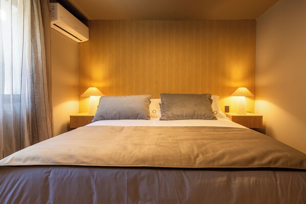 Una habitación de hotel con una cama grande, dos lámparas de noche y un aire acondicionado en la pared.