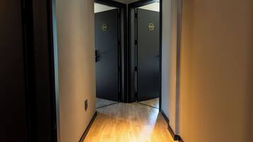Un pasillo con suelo de madera, puertas negras e iluminación empotrada.
