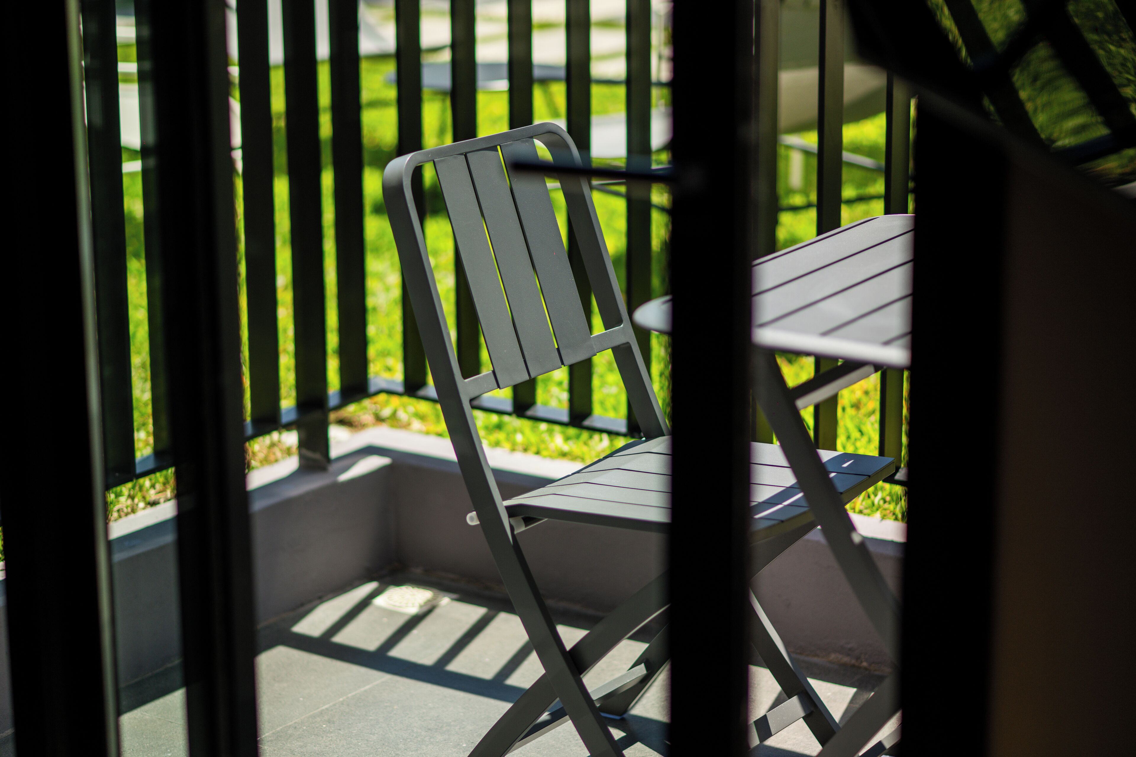 A balcony with a metal railing, a folding chair, and a table.