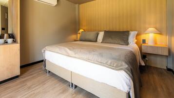 Ein Hotelzimmer mit Bett, Nachttischlampen, einer Kaffeemaschine und einem Spiegel.