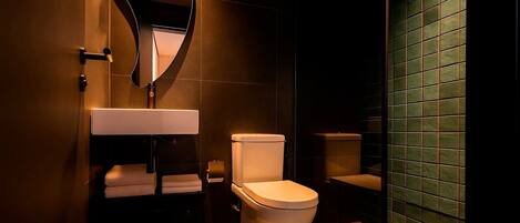 Un baño moderno con inodoro blanco, lavamanos con espejo y un perchero para toallas.