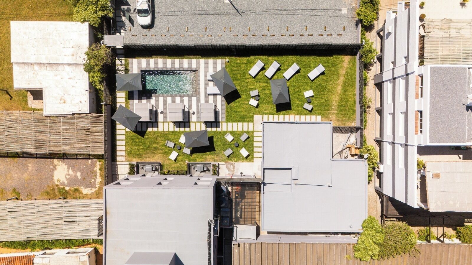 Luchtfoto van een dak met meerdere loungegedeeltes, een zwembad en een parkeerplaats.