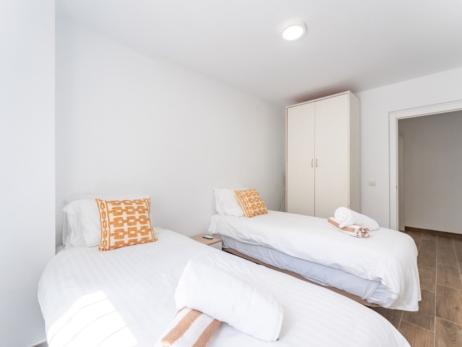 Ein Hotelzimmer mit zwei Betten, weißer Bettwäsche und einem Kleiderschrank.