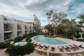 Ein modernes Hotel mit Pool, Liegestühlen und einem Garten.