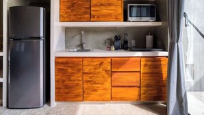 A compact kitchen with a built-in refrigerator, wooden cabinets, a microwave, and a sink. - Seremonia Origen | Tú estudio con piscina privada (Tulum)