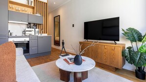 A modern living room with a round coffee table, a sofa, a TV, and a wooden cabinet.
