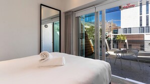 Una camera d'albergo con un letto, una poltrona e vista su un edificio con il cartello 'stayeasy'.