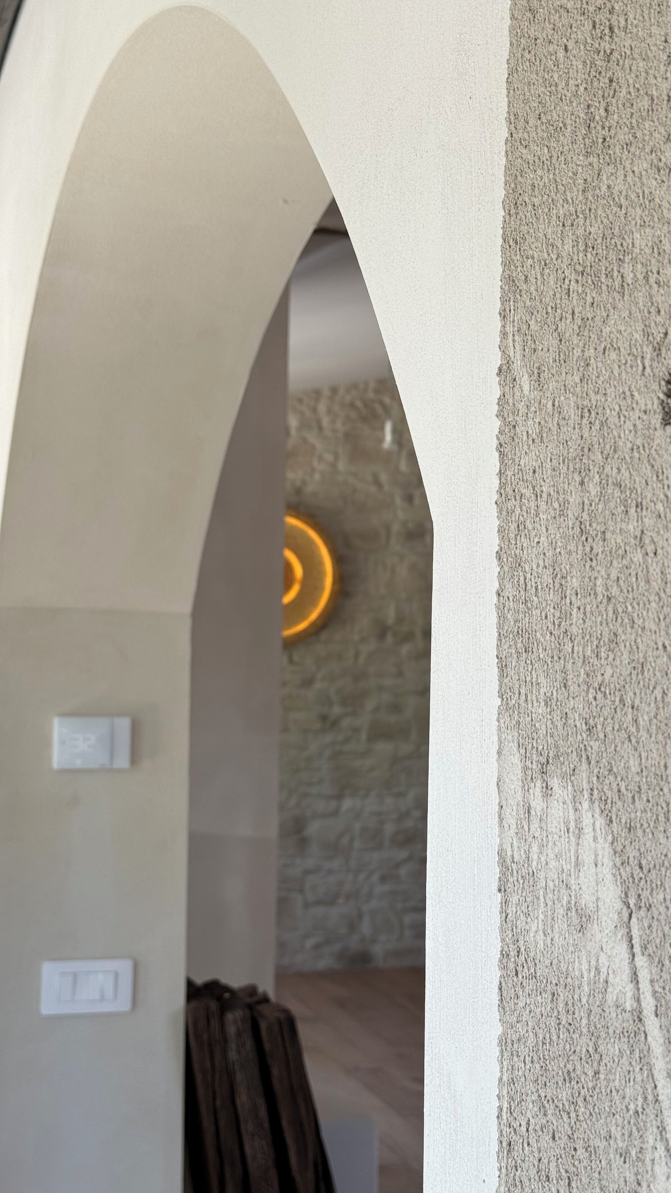 An interior space with a concrete wall, a stone wall, and a circular light fixture.