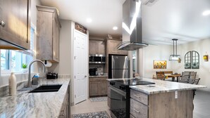 A modern kitchen with a large island, stainless steel appliances, and wooden cabinetry.
